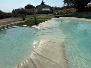 A swimming pool with clear water, a grassy area, and a building in the background.