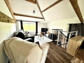 A loft-style room with a wooden floor, a sofa, a chair, a TV, and a staircase. - VILLA 5*- 12 PERSONS PMR= ALL HANDICAPS, ELEVATOR, SPA, SWIMMING POOL, VINEYARD (Casseuil)