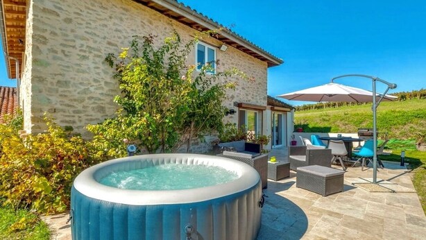 Ein Steinhaus mit Whirlpool, Gartenmöbeln und einer Terrasse.