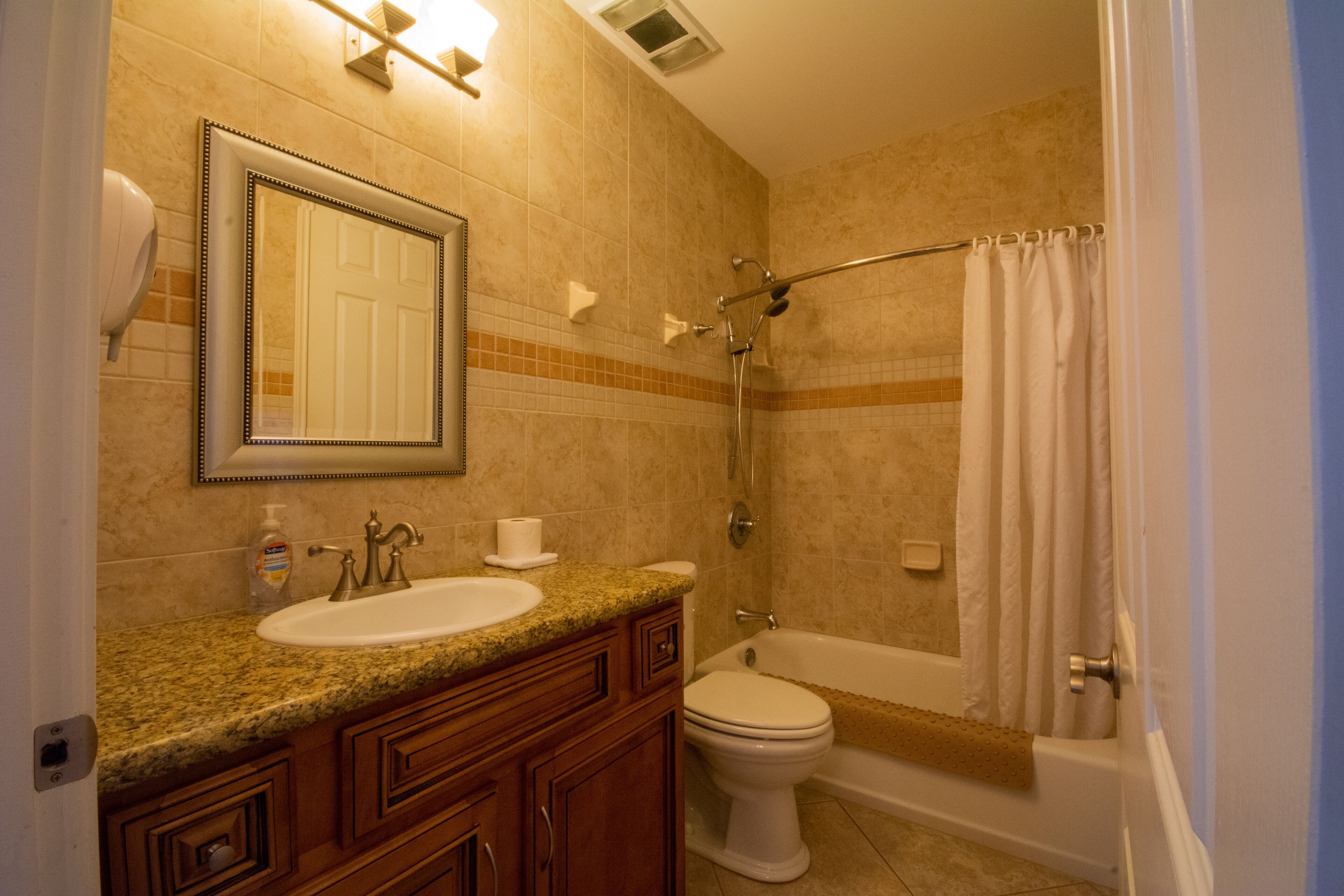 Un baño con lavamanos, espejo, inodoro y bañera.