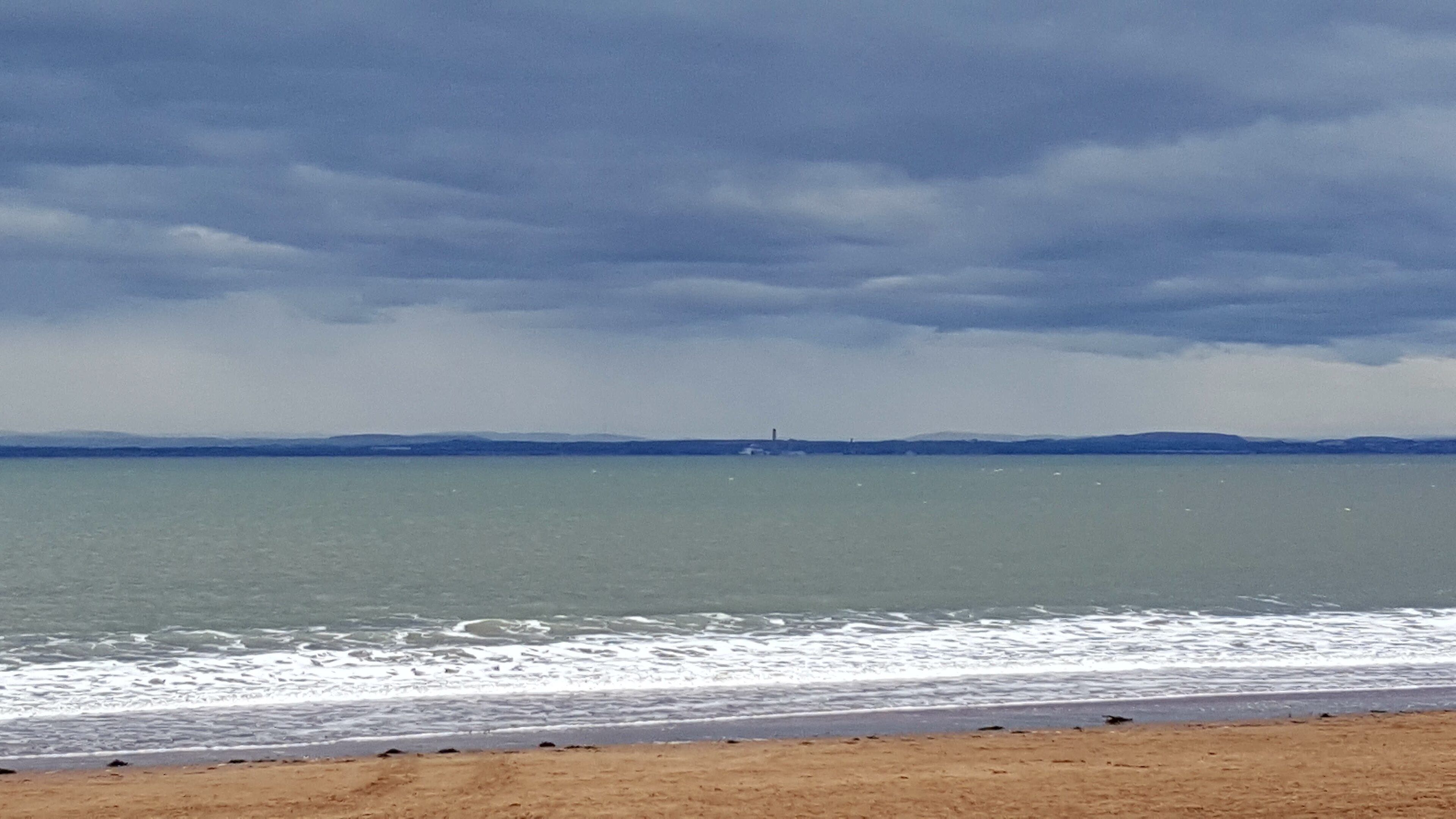 Une plage avec un rivage sablonneux et une mer calme.