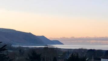 A coastal landscape with a view of the sea and distant mountains.