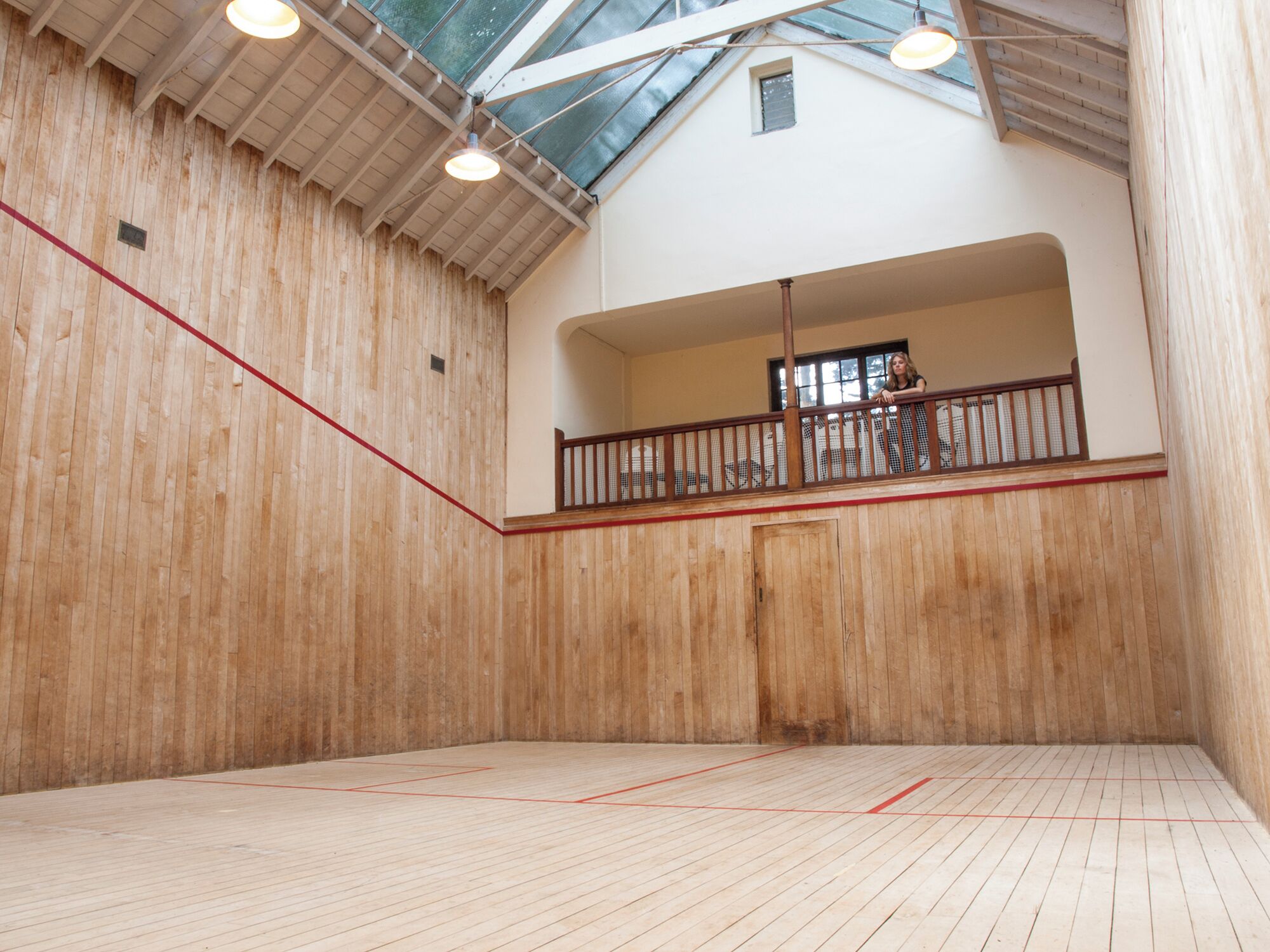 An indoor squash court with wooden walls and a sloped ceiling.