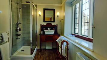 A bathroom with a glass-enclosed shower, a wooden vanity, a mirror, and a window providing natural light.