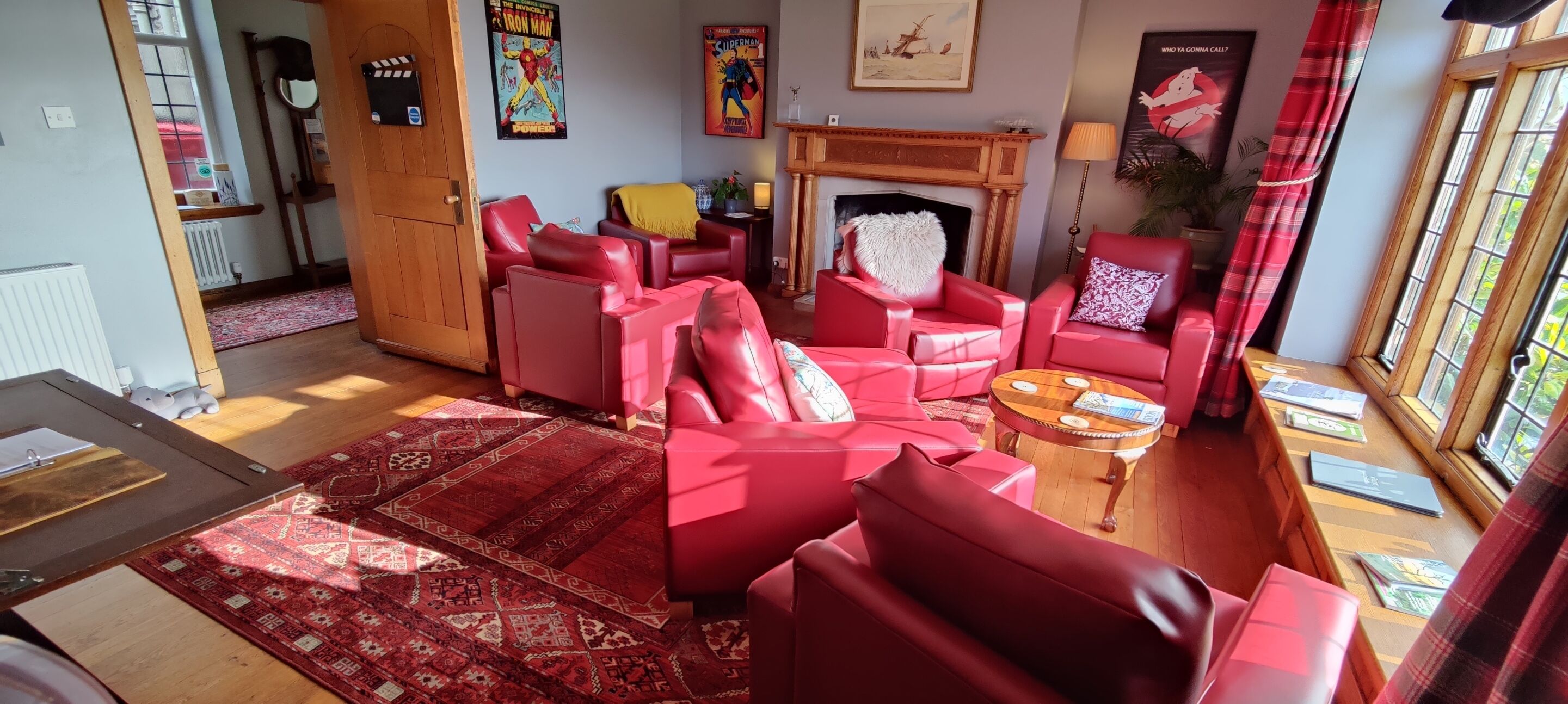 A living room with red leather sofas, a fireplace, and a large window with curtains.