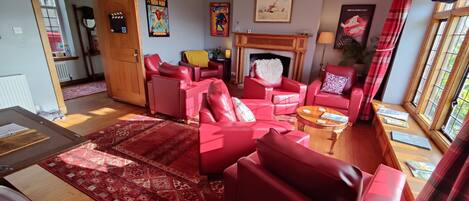 A living room with red leather sofas, a fireplace, and a large window with curtains.