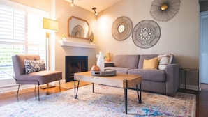 Una sala de estar con chimenea, un sofá, una mesa de centro y decoración en la pared.
