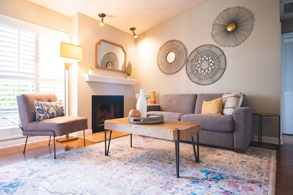 Una sala de estar con chimenea, un sofá, una mesa de centro y decoración en la pared.