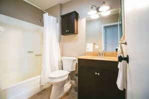 Un baño con bañera, inodoro y tocador con espejo.