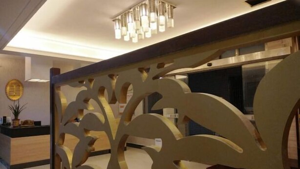A modern interior with a decorative partition, a reception desk, and a ceiling light fixture. - Xindeli Apartment (Lufeng)