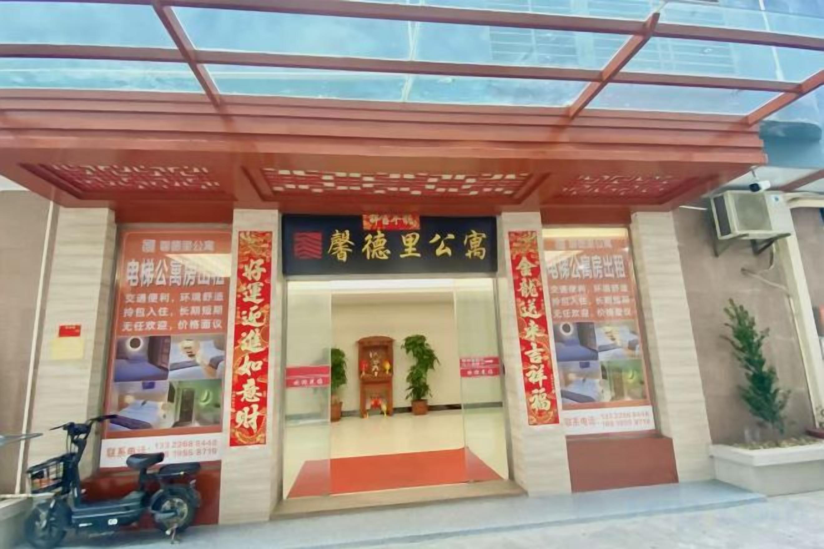 Entrada de un edificio con toldo rojo, cartel y alfombra roja que conduce a la puerta.