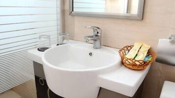 Un baño con un lavabo blanco, un espejo y una cesta de artículos de aseo.