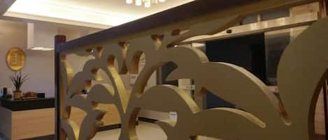 A reception area with a decorative partition, a reception desk, and a chandelier.