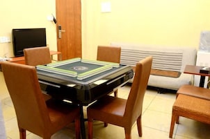 Una habitación con una mesa preparada para cuatro personas, un sofá, un televisor y una puerta.