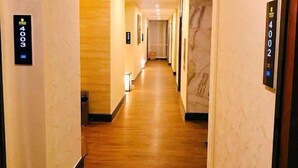 A hotel hallway with wooden flooring and numbered doors, leading to rooms. - Xindeli Apartment (Lufeng)