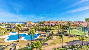 A resort with a pool area, palm trees, and a view of the sea. - Casares Beach Doña Julia Golf Apartment With Private Garden Direct Pool Access (Casares)