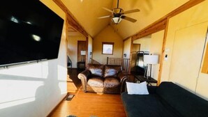 A cozy living room with a flat-screen TV, a ceiling fan, a leather sofa, a dark couch, and a fluffy rug. - Slick Rock Retreat (Moab)
