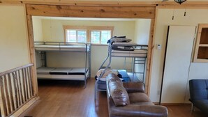 A room with bunk beds, a leather sofa, and a wooden floor. - Slick Rock Retreat (Moab)