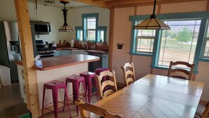 A kitchen with a central island, wooden chairs, and a dining table. - Slick Rock Retreat (Moab)