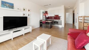 A modern living room with a flat-screen TV, white entertainment unit, and a red sofa. - Baleal Balcony - Sea & Beach view (Peniche)