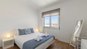 A bedroom with a bed, bedside tables, a window with a view, and a mirror. - Baleal Balcony - Sea & Beach view (Peniche)