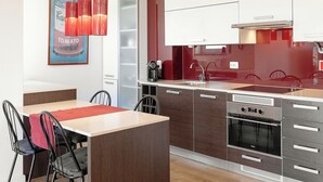 A modern kitchen with a central island, wooden flooring, and a dining area with chairs. - Baleal Balcony - Sea & Beach view (Peniche)