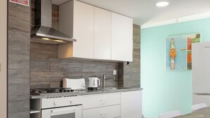 Une cuisine moderne avec des armoires blanches, un four encastré et un coin repas comprenant une table et des chaises en bois.