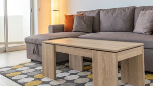 A modern living room with a grey sectional sofa, a wooden coffee table, and a patterned rug. - Baleal Dream - front of the beach (Peniche)