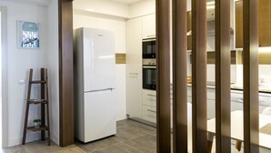 A modern kitchen with a white refrigerator, wooden cabinets, and a built-in oven. - Baleal Dream - front of the beach (Peniche)