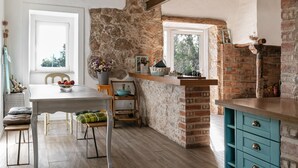 Una cocina rústica con pared de piedra, vigas de madera y un armario azul.