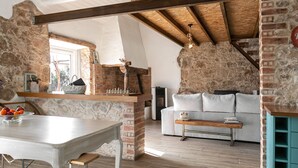 Un interior rústico con paredes de ladrillo visto, techo de madera, sofá blanco y una mesa de comedor con fruta.