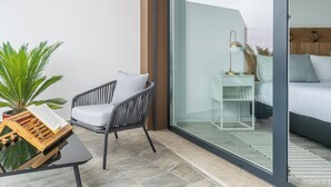 A modern balcony with a wicker chair, a small table with a book, and a potted plant. - Swell House - Stylish Baleal Beach Apartment (Peniche)