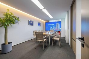 A conference room with a table, chairs, a potted plant, and a digital screen displaying a cityscape. - ZHEJIANG BUILDING HOTEL BEIJING (Beijing)