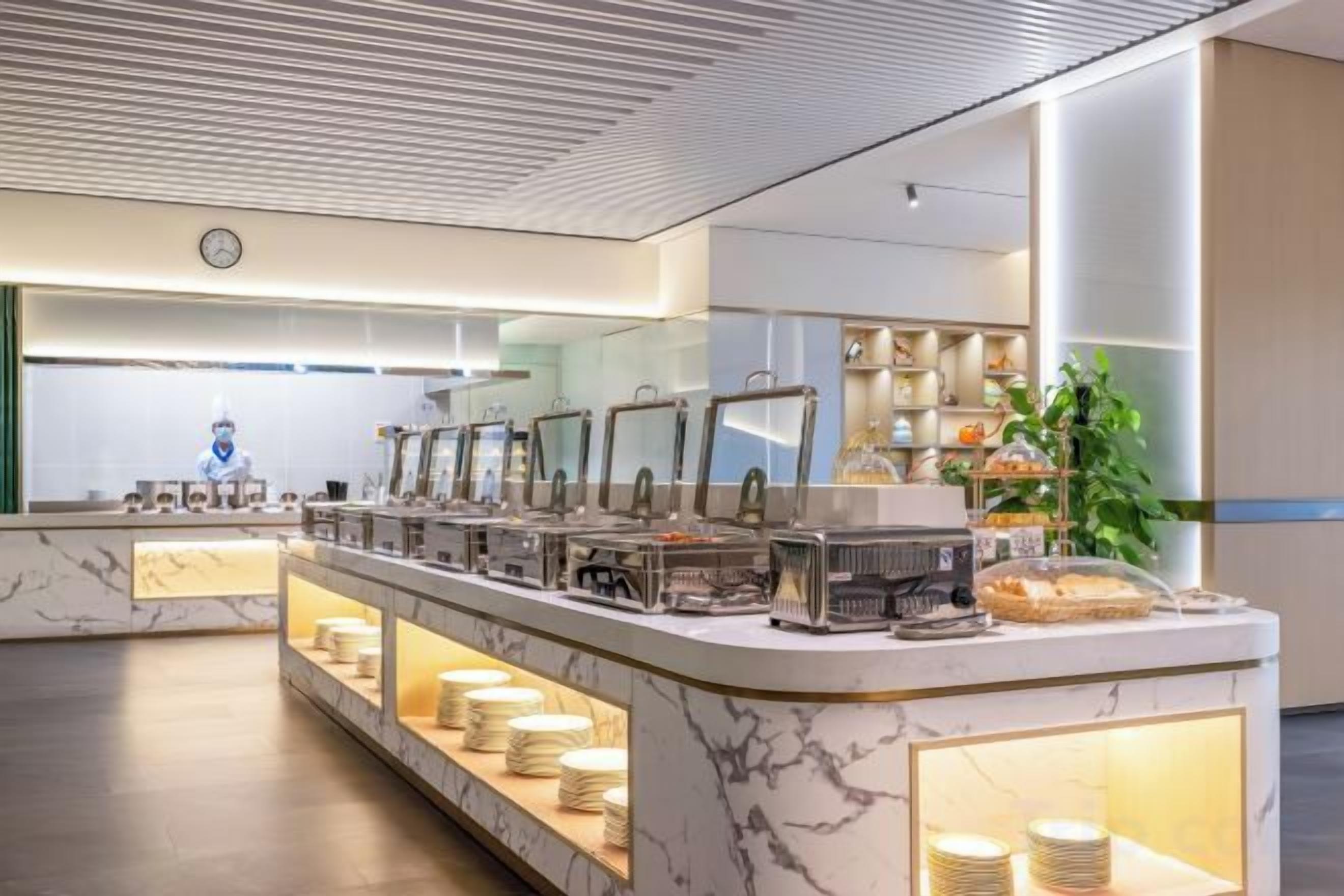 Un buffet avec plusieurs points de service, une horloge au mur et une plante en arrière-plan.
