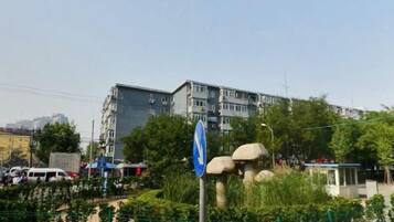 A multi-story building with a blue sign, surrounded by greenery and a fence.