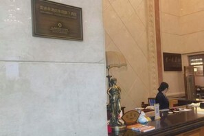 Un comptoir d’accueil avec une plaque, une statue et un présentoir où sont exposés divers objets.
