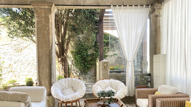 A cozy room with wicker furniture, a potted plant, and a view of greenery outside. - SEÑORIAL HOUSE ON THE COAST WITH WONDERFUL PORCH (Villagarcía de Arosa)