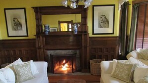 A cozy living room with a fireplace, two white sofas with patterned cushions, and framed artwork on the walls. - Victorian Mansion at Carter House Inns (Eureka)