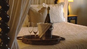 A bed with a canopy, a bottle of champagne, and two glasses on a tray. - Victorian Mansion at Carter House Inns (Eureka)