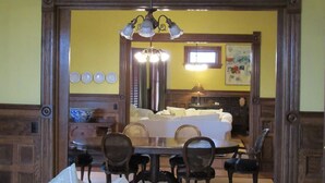 A dining area with a wooden table and chairs, a chandelier, and a white sofa in the background. - Victorian Mansion at Carter House Inns (Eureka)