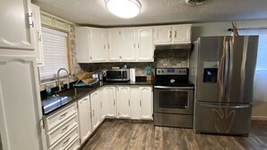 A kitchen with white cabinets, a stainless steel refrigerator, a microwave, and an oven.