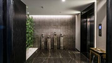 A modern elevator interior with a marble floor, a wall-mounted plant, and a digital control panel.