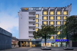 A multi-story hotel with a modern facade, balconies on each floor, and a well-lit entrance.
