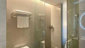 A modern bathroom with a glass shower enclosure, a toilet, and a towel rack.