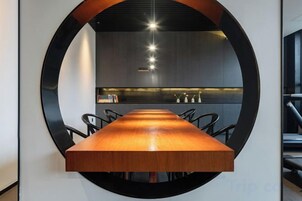 Ein Konferenztisch mit Stühlen, ein kreisförmiges Wanddesign und eine moderne Küche im Hintergrund.