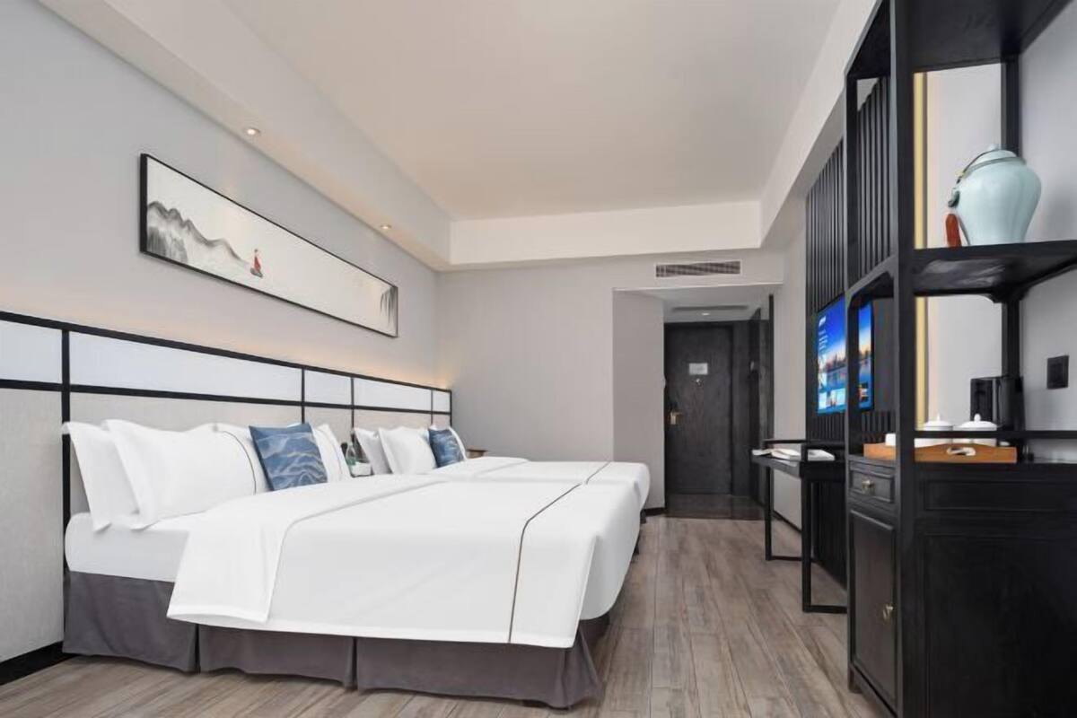 A modern hotel room with a large bed, a flat-screen TV, and a minimalist decor.