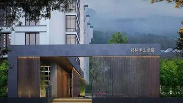 A modern hotel entrance with a prominent sign, a covered walkway, and a view of the surrounding area.