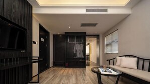 A modern hotel room with a wooden floor, a sofa, a coffee table, a TV, and a sliding door closet. - Junlin Banshan Hotel (Chenzhou)