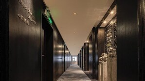 A long, narrow hallway with dark wooden walls and a patterned floor. - Junlin Banshan Hotel (Chenzhou)