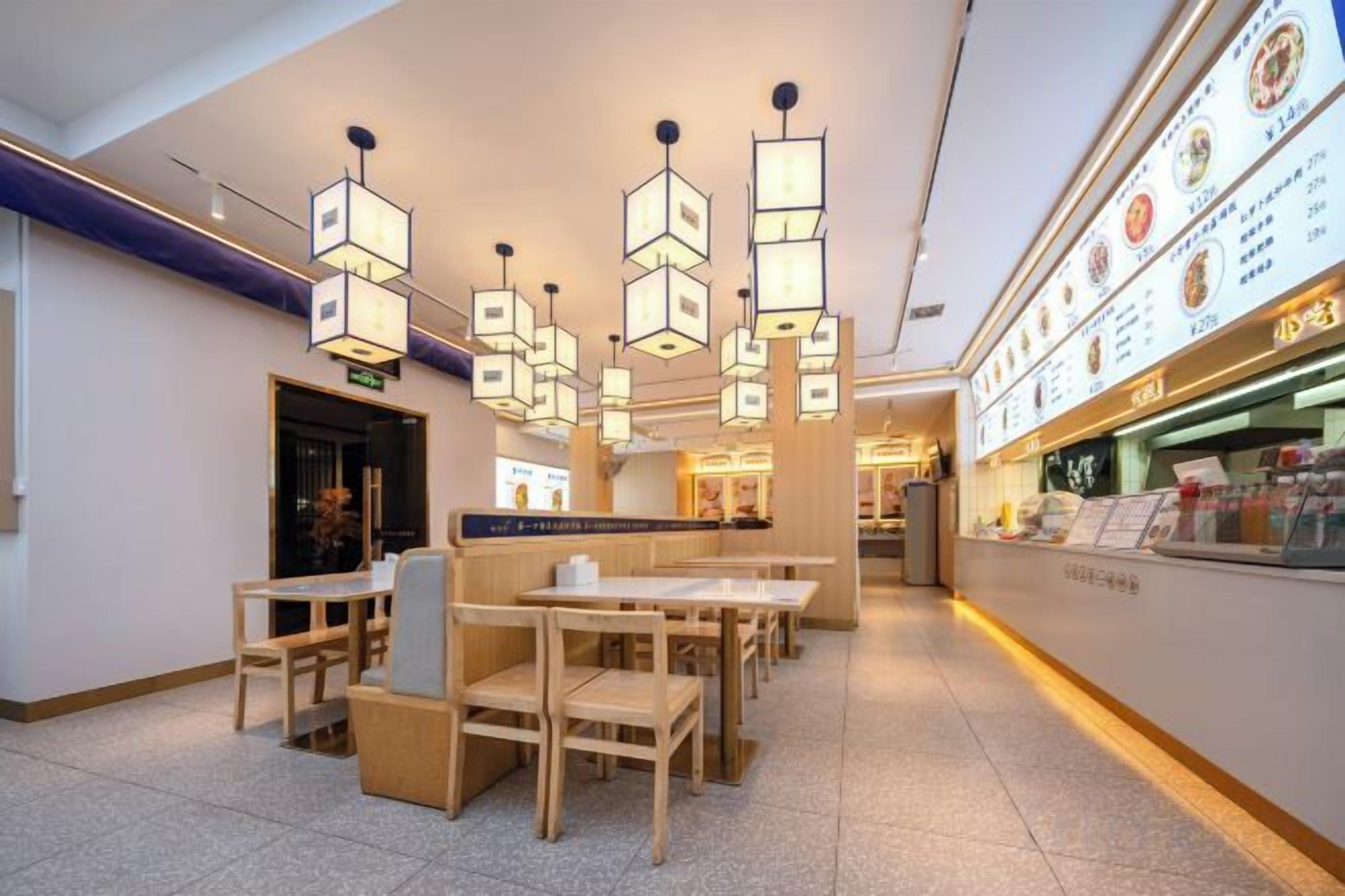 Un restaurante con mesas y sillas de madera, lámparas colgantes y una vitrina con el menú.